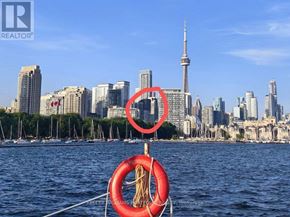 Toronto (Waterfront Communities) condo for rent - A red life preserver is in the foreground of a city skyline with the CN Tower visible.