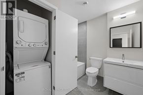 Ottawa condo for rent - A white bathroom with a toilet, sink, and a washing machine in the corner.