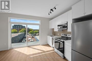 Ottawa condo for rent - A kitchen with white appliances and cabinets with a view of a pool and buildings outside.