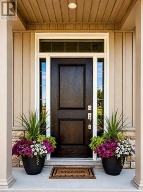 Niagara-On-The-Lake (Town) townhouse for rent - A brown door with a glass window above it and two potted plants on either side.
