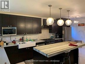 Toronto (Willowridge-Martingrove-Richview) apartment for rent - A kitchen with a wooden table and black cabinets.