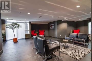 Toronto (Dovercourt-Wallace Emerson-Junction) condo for rent - A living room with a black couch and a red chair.