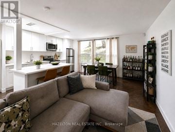 Toronto (Rosedale-Moore Park) condo for rent - A living room with a grey couch and a white kitchen in the background.