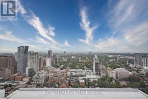 Toronto (Annex) condo for rent - A cityscape with buildings of various heights and a clear sky with clouds.