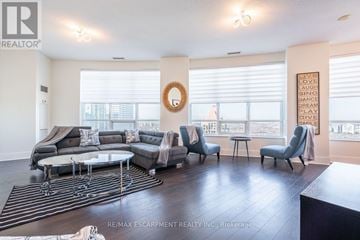 Mississauga (City Centre) condo for rent - A living room with a grey sofa set and a wreath on the wall.