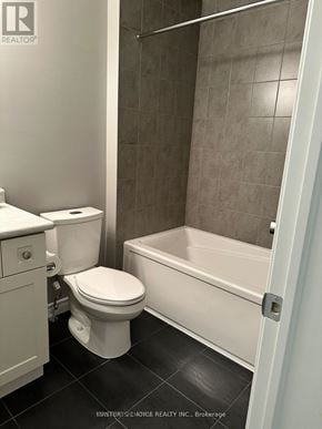 Guelph (Grange Road) townhouse for rent - A white toilet sits next to a bathtub in a bathroom.