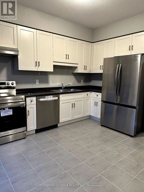 Guelph (Grange Road) townhouse for rent - A kitchen with white cabinets and a stainless steel refrigerator.