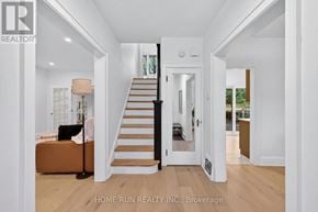 Ottawa apartment for rent - A white hallway with a staircase and a doorway leading to another room.