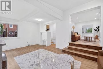 Ottawa apartment for rent - A spacious living room with a rug on the floor and a staircase leading to the upper floor.