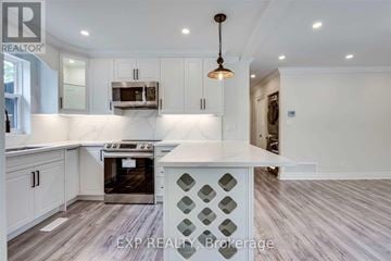 Hamilton (Eastmount) apartment for rent - A kitchen with white cabinets and a wooden floor.