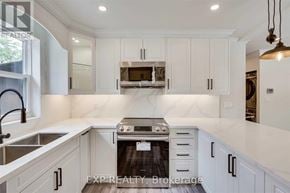 Hamilton (Eastmount) apartment for rent - A modern kitchen with white cabinets and a stove top oven.