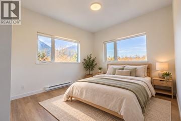 Squamish apartment for rent - A bedroom with a large bed and a view of the outdoors through the windows.