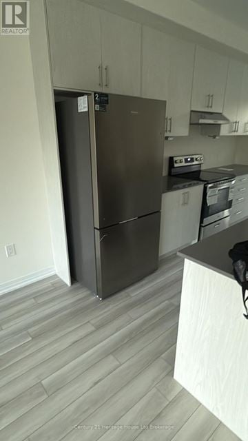 Woodstock (Woodstock - South) townhouse for rent - A kitchen with a refrigerator and a stove top oven.