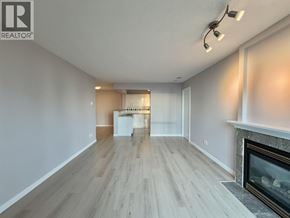 Burnaby apartment for rent - A spacious living room with a fireplace and a dining area in the background.