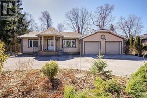 Georgina (Keswick South) apartment for rent - A house with a brown roof and a garage door is surrounded by a gravel driveway and some bushes.