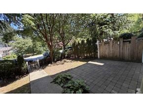 Surrey townhouse for rent - A backyard with a tree, a fence, and a paved area.