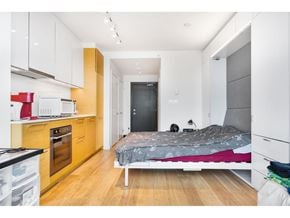 Surrey apartment for rent - A small bedroom with a bed, dresser, and a small kitchen area.