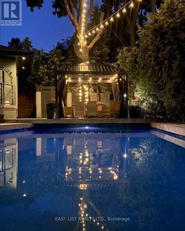 Toronto (Princess-Rosethorn) apartment for rent - A pool with a house and a tree with lights in the background.