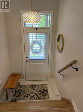 Kawartha Lakes (Bobcaygeon) townhouse for rent - A white door with a glass window is flanked by a wooden bench and a wall-mounted shelf.