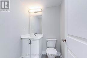 Clarington (Bowmanville) triplex for rent - A white bathroom with a toilet, sink and mirror.