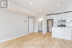 Clarington (Bowmanville) triplex for rent - A white kitchen with wooden floors and a white fridge.
