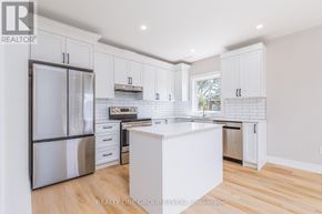 Clarington (Bowmanville) triplex for rent - A white kitchen with a refrigerator, oven, and sink.