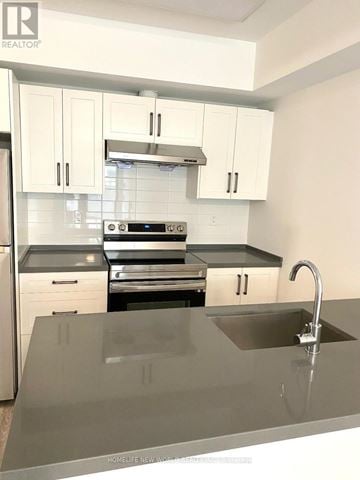 Toronto (L'amoreaux) townhouse for rent - A kitchen with white cabinets and a black countertop.