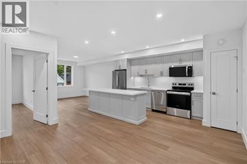 Dundas apartment for rent - A modern kitchen with white cabinets and a wooden floor.