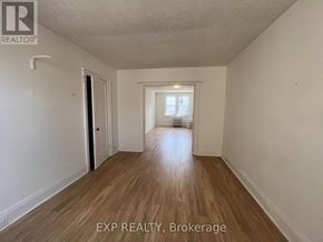 Toronto (Wychwood) multi-family for rent - A room with wooden flooring and white walls, with a door on the left and a window on the right.
