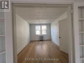 Toronto (Wychwood) multi-family for rent - A room with wooden floors and white walls, with a window and a radiator.