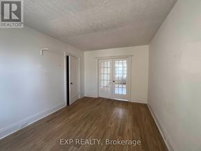 Toronto (Wychwood) multi-family for rent - A room with wooden flooring and white walls, with a door and a window.