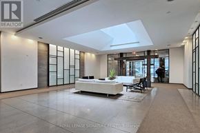 Toronto (Niagara) condo for rent - A spacious living room with a white sofa and a glass partition wall.