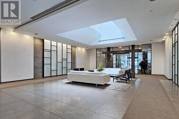 Toronto (Niagara) condo for rent - A spacious living room with a white sofa and a glass partition wall.