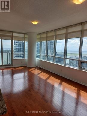 Toronto (Waterfront Communities) condo for rent - A large room with wooden floors and a view of the city through the windows.