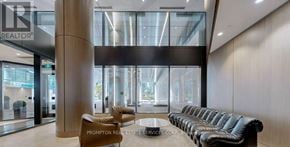 Toronto (Waterfront Communities) condo for rent - A modern waiting area with a long black leather couch and a wooden floor.