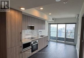 Toronto (Waterfront Communities) condo for rent - A modern kitchen with wooden cabinets and stainless steel appliances.