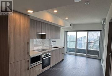 Toronto (Waterfront Communities) condo for rent - A modern kitchen with wooden cabinets and stainless steel appliances.