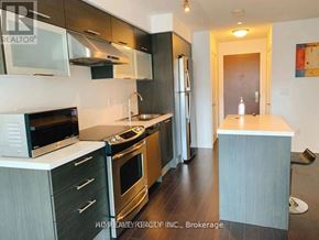Toronto (Bay Street Corridor) condo for rent - A modern kitchen with dark wood floors and stainless steel appliances.