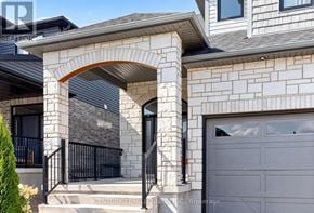 East Luther Grand Valley (Grand Valley) apartment for rent - A house with a grey garage door and a stone archway entrance.