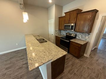 Temple townhouse for rent - A kitchen with a granite countertop and wooden cabinets.