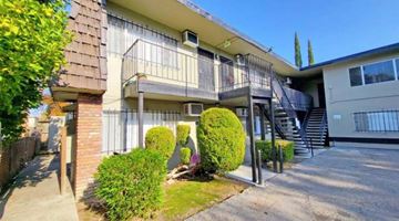 Stockton apartment for rent - A two-story apartment building with a balcony and a small garden in front.