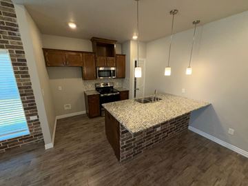 Temple townhouse for rent - A kitchen with a granite countertop and wooden cabinets.