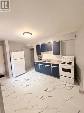 Ottawa multi-family for rent - A kitchen with a white fridge, white stove, and blue cabinets.