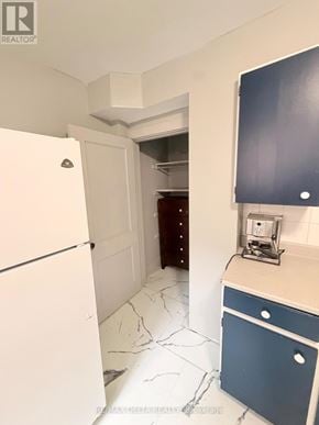 Ottawa multi-family for rent - A kitchen with a white fridge and blue drawers.