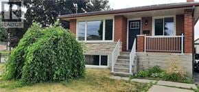 Kitchener apartment for rent - A house with a blue door and a large green bush in front.