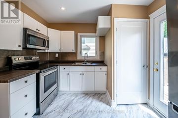 Niagara Falls (Downtown) apartment for rent - A kitchen with white cabinets and a black stove top oven.
