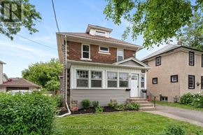St. Catharines (Downtown) apartment for rent - A house with a red brick chimney and a white door is surrounded by greenery.