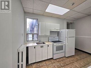 Toronto (Church-Yonge Corridor) multi-family for rent - A kitchen with white appliances and cabinets is shown.