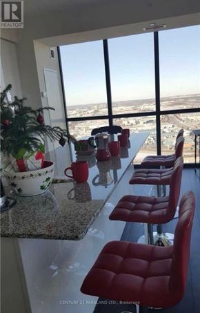 Vaughan (Concord) condo for rent - A kitchen with red chairs and a view of the city.