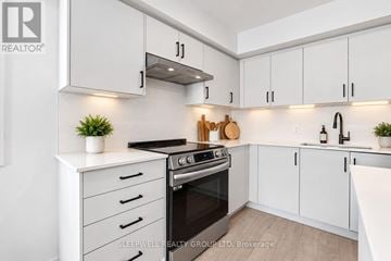 Ottawa multi-family for rent - A modern kitchen with white cabinets and a black stove top.